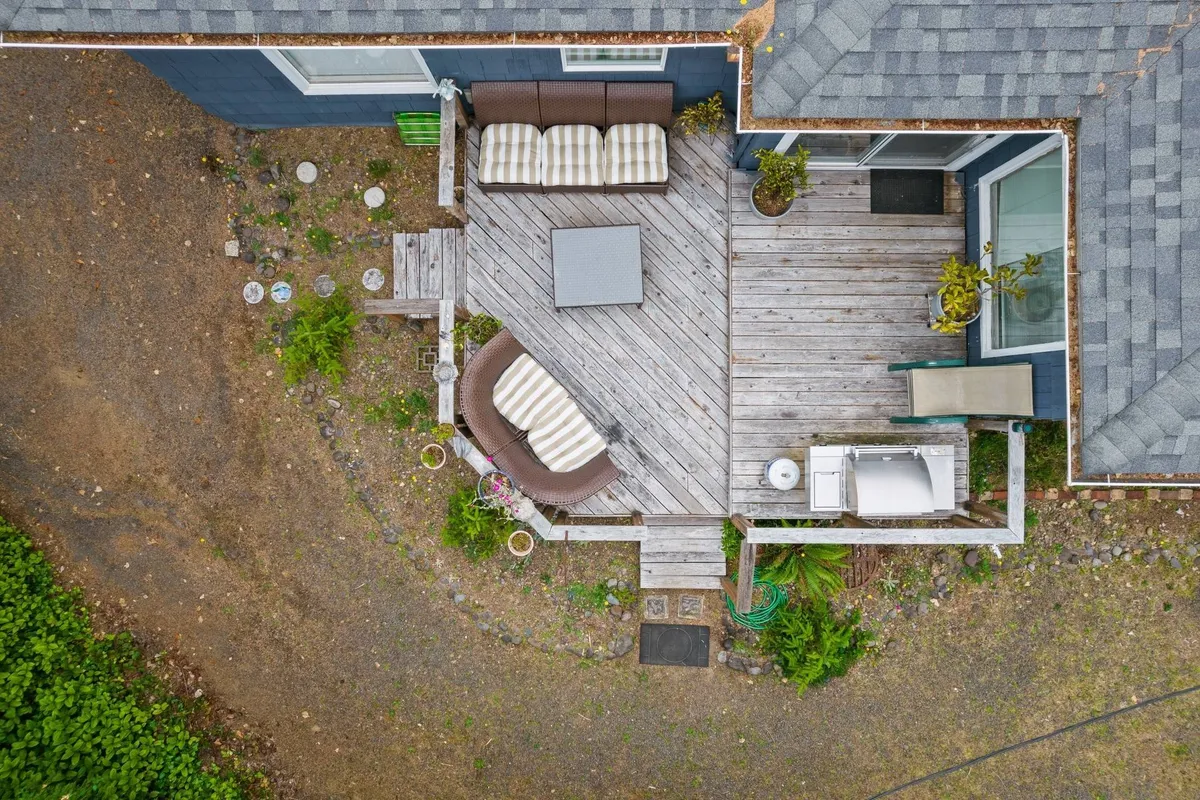 An inviting outdoor seating area featuring a coffee table and comfortable chairs, nestled within abundant greenery. The space is styled for relaxation, morning rituals, or evening gatherings under the trees.