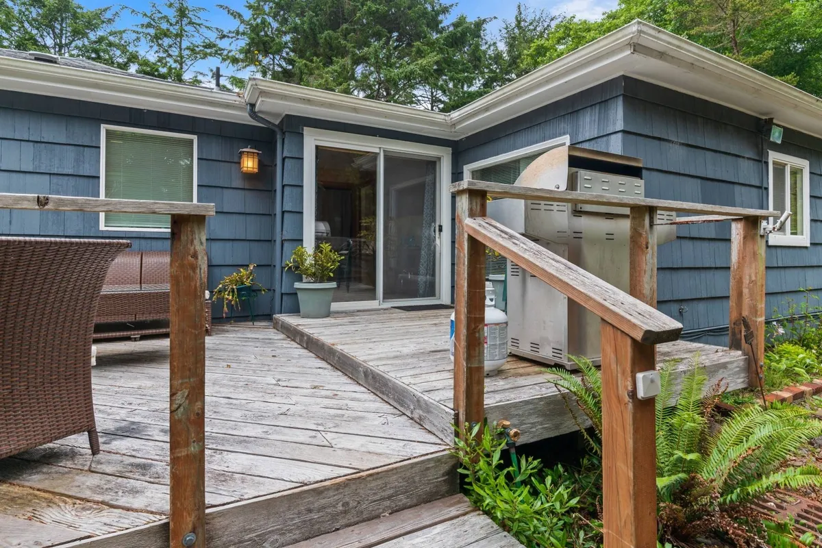 This image showcases a welcoming deck space featuring a BBQ grill, comfortable seating area, planters bursting with greenery, and a view of the surrounding natural landscape. The setup is ideal for outdoor dining, lounging, and enjoying the tranquility of the outdoors, embodying the essence of a private outdoor escape.